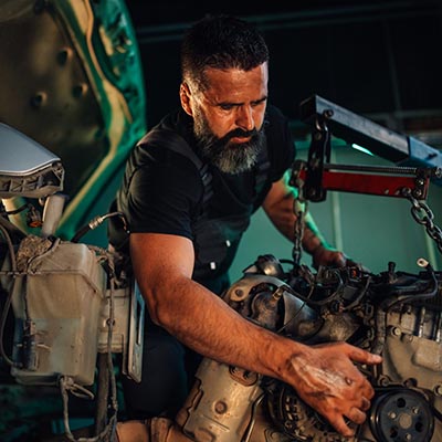 A diligent mechanic uses a wrench to perform maintenance on a car engine, reflecting his technical skills and dedication in a well-organized garage workspace.